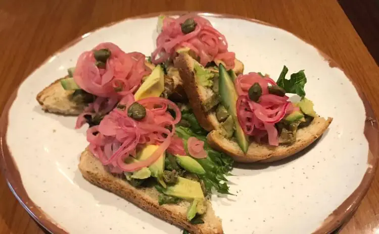 a white plate topped with slices of bread covered in toppings