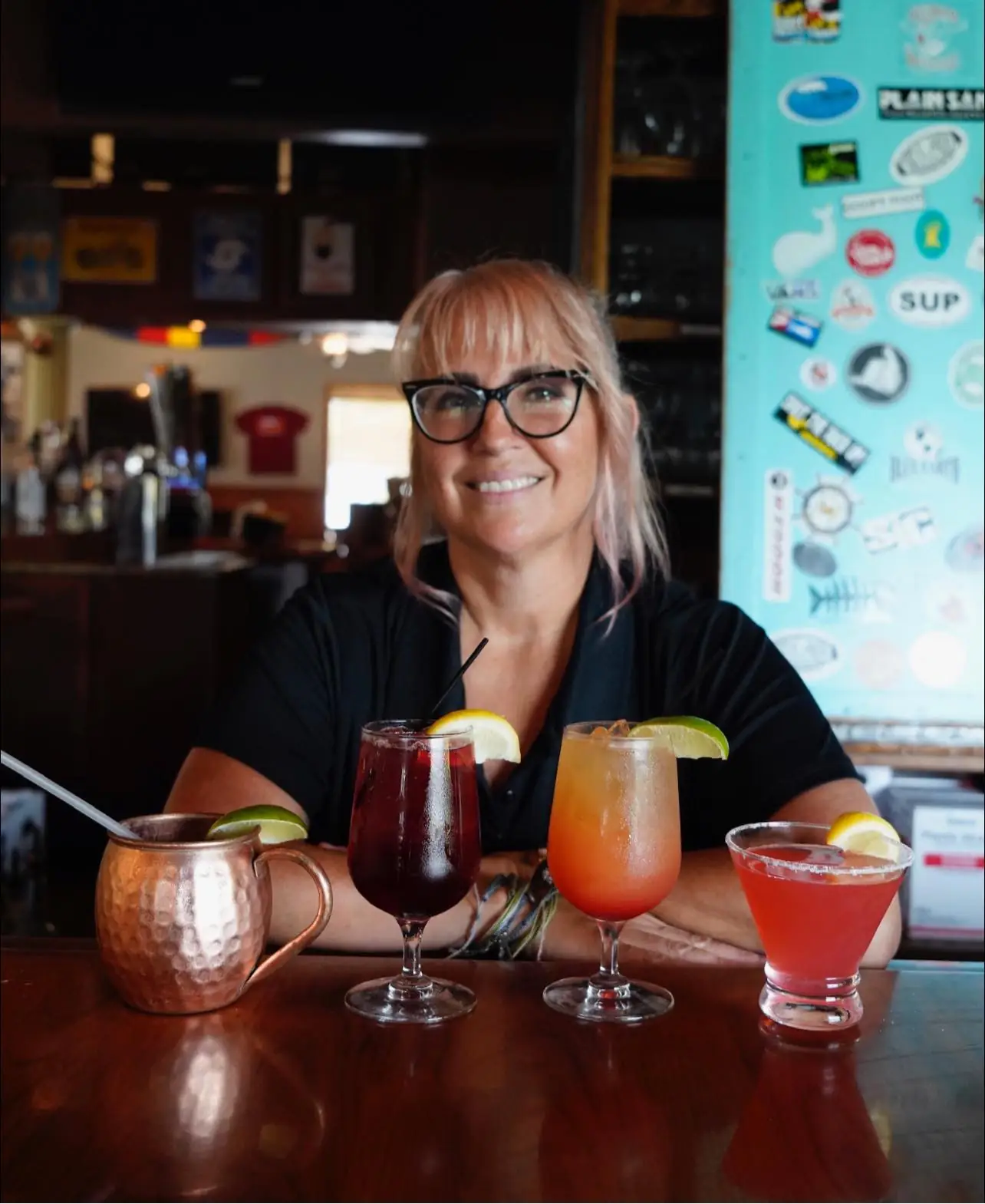 a woman sitting at a bar with three different drinks