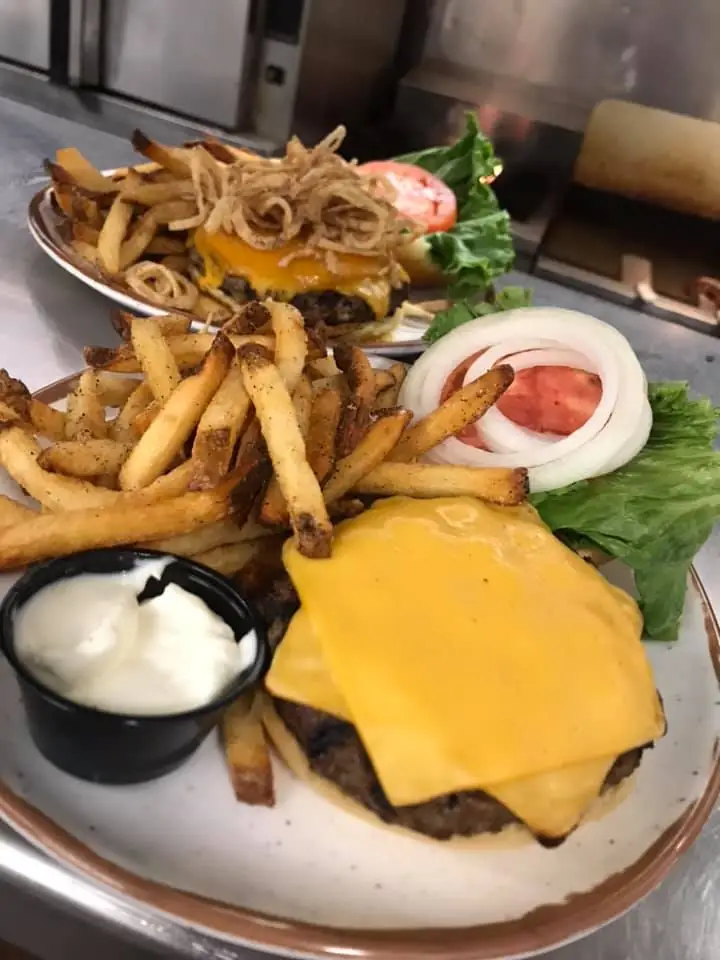 a hamburger with cheese and fries on a plate